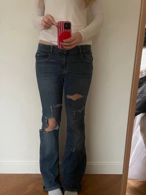 Blå bootcut jeans med slitningar - Säljer dessa svin coola jeansen med hål från Zara. Jätte skönt matrial, bootcut och lågmidja. Hål vid ljumsken men inget som syns. 🥰🥰