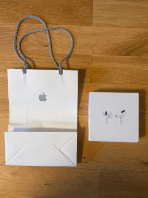 AirPods Pro med MagSafe Charging Case - Säljer ett par AirPods Pro med MagSafe-laddningsetui, komplett med originalförpackning och manualer. Produkten ser ut att vara i nyskick utan synligt slitage. Perfekt för dig som vill ha aktiv brusreducering och hög ljudkvalitet. Levereras med Apple-presentpåse.