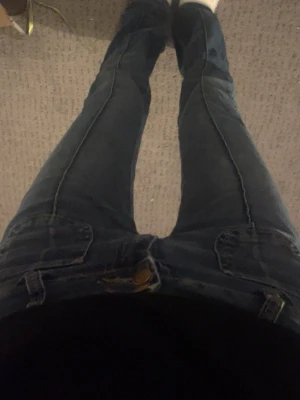 Blå bootcut jeans från Madlady - Säljer ett par blå bootcut jeans från Madlady i storlek EU32/EX-TALL. Jeansen har klassisk femficksdesign, guldiga knappar och är tillverkade i jeansmaterial. Passformen är normal med lite utsvängda ben och hög midja. Perfekta för dig som gillar längre jeans.