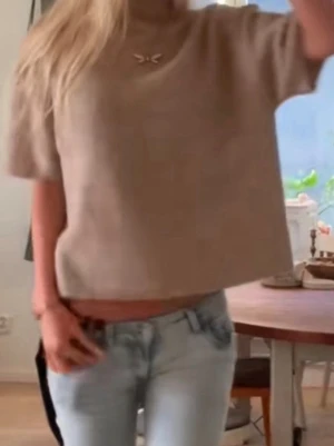 Beige stickad polotröja med kort ärm - Supermjuk och stilren beige stickad polotröja med korta ärmar och boxig passform. Tröjan har ribbad hög krage och är perfekt att styla med både jeans och kjol. Enkel och clean look som funkar året runt.