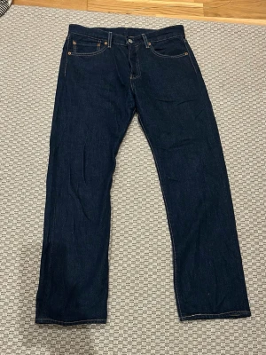 Levi's 501  - Säljer ett par klassiska Levi's 501 jeans i mörkblå denim. Modellen har rak passform och är tillverkad i slitstarkt bomullsmaterial. Perfekt för dig som gillar tidlös stil och vill ha ett par jeans som funkar till allt. Levi's patch bak i midjan.