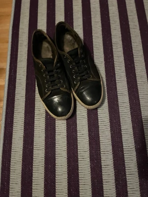 Svarta Lanvins - Lanvin sneakers i svart mocka med glans. Snygga sköna skor som passar till massa olika outfits! Perfekt för dig som gillar mode! Slitna men har mycket kvar i sig. Pris kan diskuteras privat! 
