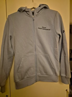 Peak Performance Hoodie - Peak performance hoodie i färg ljusblå i storlek S. Använd 2ggr, mycket fint skick. Ser ny ut på utsidan.
