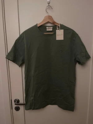 Grön t-shirt från GANT - Snygg grön t-shirt från GANT, aldrig använd och sitter fortfarande med prislappen på! Nypris på tröjan ligger på 600kr men jag säljer den för 349kr! Hör gärna av dig om du har frågor.
