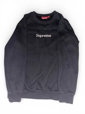 Svart Supreme sweatshirt i bomull - Supreme crewneck i svart med klassisk box logo broderad på bröstet. Tröjan är tillverkad i 100% bomull och har ribbade muddar vid ärmslut och nederkant. Perfekt för dig som gillar streetwear och vill ha en clean look med ikonisk branding.