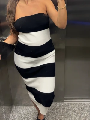 Ribbad randig tubklänning från H&M - Säljer en bandeau klänning med breda svarta och vita ränder. Från H&M. 