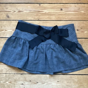 Rutig minikjol  - Så fin rutig minikjol från Atmosphere med rosett🖤🩶längd: ca 29cm, midja rakt över: 36cm.