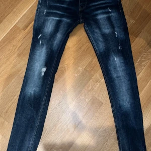 Philipp Plein blå jeans straight fit - Hej!  Säljer ett par blå jeans från Philipp Plein med straight fit.  Jeansen har slitna detaljer och coola kontrastsömmar, samt ett unikt märke med silverdetaljer bak.  Klassisk femficksmodell och dragkedja framtill.  Perfekta för dig som gillar tajta byxor.  Vill du veta något mer eller vill ha fler bilder så är det bara att skriva! Priset är såklart inte hugget i sten!