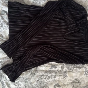 Svart ribbad polotröja - Säljer en svart ribbad polotröja med lång ärm och hög krage. Tröjan har ett smalt, stretchigt tyg med tydliga vertikala ränder som ger en snygg struktur. Perfekt för lager-på-lager och passar till både jeans och kjol.