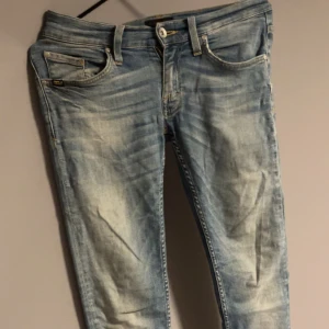 Tiger of Sweden jeans  - Snygga ljusblå skinny jeans från JJ med slitningar och tvättade detaljer. Klassisk femficksmodell med bälteshällor och knappgylf. Perfekta för dig som gillar en smal passform och en avslappnad look.
