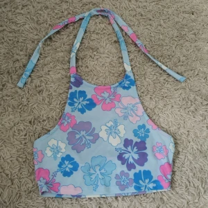Blommig halterneck med öppen rygg - Supersöt överdel med blommigt mönster i blått, rosa, lila och vitt. Hög halsringning och knyt i nacken. Perfekt för stranden eller en härlig sommardag, är i storlek XS från NA-KD.