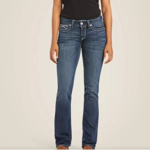 Blå bootcut jeans med kontrastsömmar - Snygga blå jeans med bootcut passform och markerade vita kontrastsömmar. Jeansen har klassiska fem fickor och dekorativa sömmar på bakfickorna. Tillverkade i stretchig denim för skön passform och stilren look.