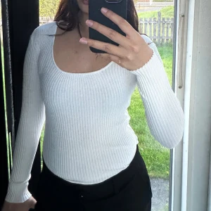 Vit ribbad långärmad body - Säljer en vit ribbad body med lång ärm och rundad, djup urringning. 