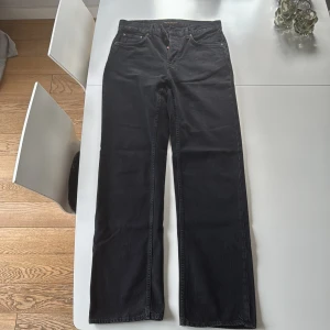 Nudie Jeans Svarta jeans , W29 L34 - Svarta jeans från Nudie Jeans med klassisk femficksdesign och raka ben. Modell Tuff Tony. Jeansen har en stilren look med svarta sömmar och subtil logga på bakfickan. Tillverkade i kraftigt denimtyg som ger en snygg passform och tidlös vibe.