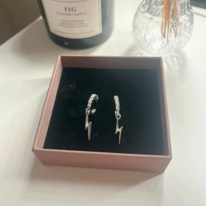 Silverörhängen med blixtberlocker - Snygga örhängen i silverfärg med små blixtformade berlocker och glittriga detaljer på ringen. Perfekt för dig som vill ha en cool och trendig look med lite edge. Tvättas med våtservetter och handsprit innan frakt. 🩷
