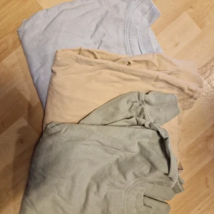 3-pack basic tröjor i pastellfärger - Tre basic tröja i mjuka pastellfärger: ljusblå, beige och ljusgrön. Alla har klassisk rund halsringning och korta ärmar. Perfekta för en clean och avslappnad stil. Säljes som paket.