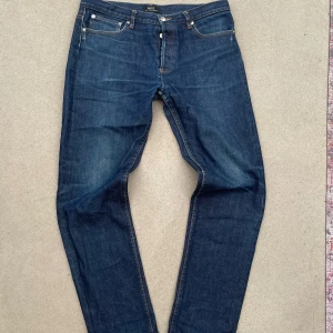 Mörkblå jeans från A.P.C. - Snygga mörkblå jeans från A.P.C. med klassisk femficksdesign och raka ben. Jeansen har orange kontrastsömmar och en stilren look utan synliga loggor på bakfickorna. Perfekta för dig som gillar minimalistisk stil och hög kvalitet.