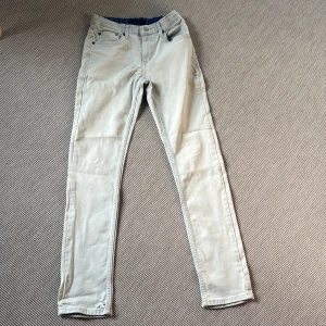 Levi's 512 ljusa skinny jeans - Snygga ljusa Levi's 512 jeans i skinny fit med klassisk femficksdesign och dragkedja. Byxorna är i en ljusblå ton och har Levi's logga på linningen. Perfekta för dig som gillar en smal siluett och vill ha ett par stilrena jeans. Det finns fläckar (troligen oljefläckar) på baksidan av byxorna! 