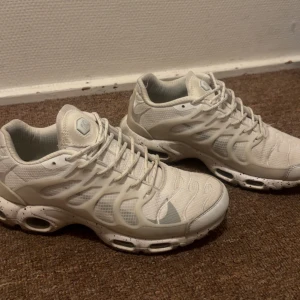 Vita Nike skor - Säljer ett par vita sneakers med coolt, futuristiskt mönster och detaljerad sula med svarta prickar. Skorna har snörning och meshpaneler för extra andningsförmåga. Snyggt plastöverdrag längs sidorna och bekväm, stötdämpande sula. Perfekta för dig som gillar streetstyle.