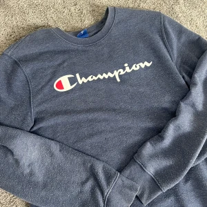 Blå Champion sweatshirt  - Blå sweatshirt från Champion i storlek L. Tröjan har klassisk rund hals, långa ärmar och stor vit logga framtill.
