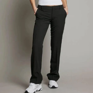 Svarta kostymbyxor från Bik Bok - Snygga svarta kostymbyxor från Bik Bok i klassisk rak modell. Byxorna har hög midja, pressveck och diskreta fickor fram och bak. Stängs med dragkedja och knapp. Perfekta till en stilren look och passar till sneakers eller boots. Nypris 500!