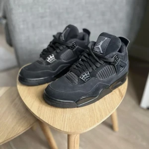 Nike Air Jordan 4 Retro Black Cat - Säljer ett par Nike Air Jordan 4 Retro Black Cat sneakers i helsvart mocka och syntet. Klassisk siluett med meshpaneler, snörning och ikoniska Jumpman-loggor på plös och sula. Riktigt clean och stilren modell som passar till allt. Har boxen tlll dom då dom e helt nya skickar dom över hela Sverige 👍 varma och sköna nu i vinter 