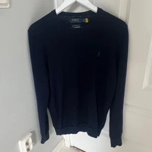 Mörkblå merinoullströja Polo Ralph Lauren - Snygg mörkblå tröja från Polo Ralph Lauren i tvättbar merinoull. Slim fit-modell med rund halsringning och diskret broderad logga på bröstet. Perfekt för dig som gillar klassisk och stilren look. Nypriss 2500 kr! 