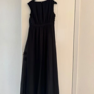 Svart långklänning med glittriga detaljer - Elegant svart långklänning med glittriga detaljer vid halsringning och midja. Storlek 40-42