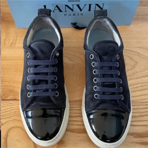 Lanvin - Snygga sneakers från Lanvin i mörkblå mocka med svart lackad tå och vita sulor. Skorna har rund tå, snörning och klassisk låg profil. Perfekta för dig som vill ha en stilren men ändå unik look. Kommer med originalpåse och box.Dom är 9/10 sick och perfekta nu inför vintern😁👊🏻