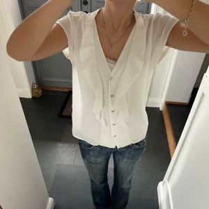 Vit kortärmad blus - Vit topp/blus med volanger och knappar från STOCKH LM i storlek 36. Fint skick. Använd gärna köp nu!