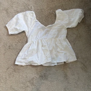 Vit omlottblus - Säljer en söt vit omlottblus med korta puffärmar. Blusen har en v-ringad design. Säljer den då den är för stor på mig