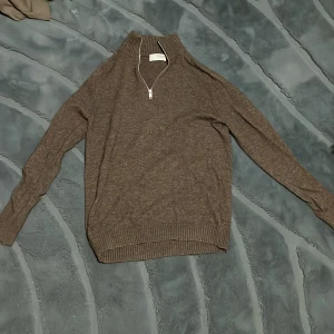 Brun stickad half zip-tröja Selected - Brun stickad tröja från Selected Homme med ribbad hög krage och half zip-dragkedja. Långärmad modell med ribbade muddar och nederkant. Perfekt för lager-på-lager och chill höst- eller vinterstil. I princip oanvänd, hör av er om ni har frågor😊