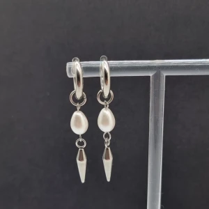 Silvriga örhängen med pärldroppe och spike - Snygga örhängen i silverfärg med rund ring, droppformad vit pärla och spetsig metallspets som hänger längst ner. Längd- 4,8cm