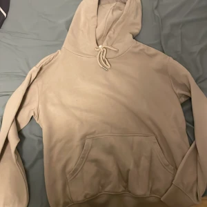 Beige hoodie från H&M Basics XS - En stilren beige hoodie från H&M Basics i storlek XS. Tröjan har huva med snörning, magficka och långa ärmar. Perfekt för en chill och avslappnad look. Mjuk insida och klassisk passform.
