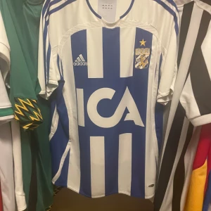 IFK Göteborg 2004 matchtröja Adidas L Äkta - Säljer en klassisk IFK Göteborg fotbollströja från 2004 av Adidas i storlek L. Tröjan är blåvit med vertikala ränder, klubbmärke och ICA-logga på bröstet.  Tröjan är mycket bra skick, Äkta