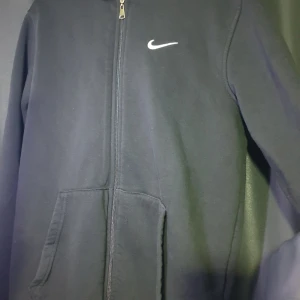 Svarta mjukisbyxor från Nike M - Svarta mjukisbyxor från Nike med klassisk vit swoosh-logga på benet. Byxorna har resår och snörning i midjan samt muddar vid bensluten för en skön passform. Perfekta för chill eller träning, tillverkade i mjukt bomullsmaterial.