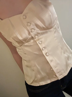Korsett topp - Korsett liknande topp, går att knäppa upp helt. Aldrig använd, ny utan prislapp. Storlek 34.