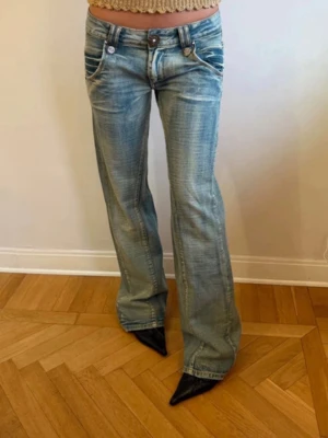 Blå bootcut jeans från Miss Sixty - Snygga ljusblå bootcut jeans från Miss Sixty med slitningar och kontrastsömmar! Jeansen har låg midja, dekorativa fickor fram och bak samt klassisk knappgylf.  Midjemått: 38cm💕