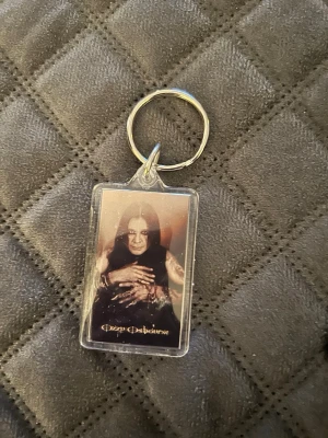 Nyckelring Ozzy Osbourne - Nyckelring med Ozzy Osbourne. Visar båda sidor. Helt ny. Lite skuggor på bilden.. 