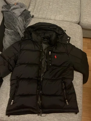 Svart pufferjacka från Polo Ralph Lauren  - Svart pufferjacka från Polo Ralph Lauren. Knappt används inga skador mer bilder eller frågor är det bara att höra av sig