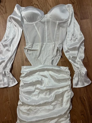 Vit korsett sett / kläning - Trendig vit sett från SHEIN med långa puffärmar och omlottdetalj.  har en figurnära passform, markerad byst och rynkad kjol i glansigt material. Perfekt för dig som vill sticka ut med en elegant look.