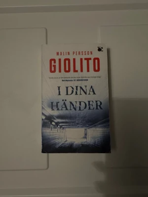 I dina händer av Giolito - En spännande pocketbok av Malin Persson Giolito med titeln 'I dina händer'. Omslaget är vitt och blått med en dramatisk tunnelbild och röd text. Perfekt för dig som gillar starka berättelser om samtiden och relationer.