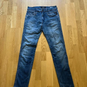 Replay Anbass jeans blå herr W31, L32 - Säljer ett par snygga Replay Anbass jeans i klassisk blå tvätt. Jeansen har fem fickor, raka ben och diskreta slitningar för en cool look. Materialet är mjukt och stretchigt jeans, perfekt för dig som vill ha både stil och komfort.