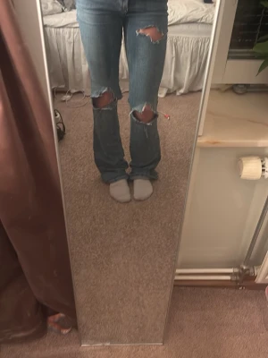 Blå bootcut jeans med slitningar från Zara - Snygga blå bootcut jeans med slitna detaljer över knäna. Jeansen har klassisk femficksdesign och är tillverkade i denim. Det är från Sara men gjort om dem själv så det går inte att köpa i butik.