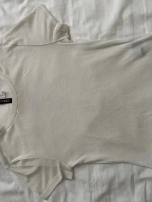 Vit basic t-shirt från H&M - En enkel och stilren vit t-shirt från H&M. T-shirten har rund halsringning och korta ärmar. Tillverkad i mjuk bomull som känns skön mot huden. Perfekt att matcha med jeans eller shorts för en clean look. Ganska genomskinlig.