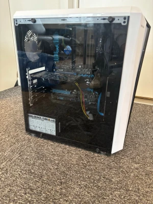 Vit stationär dator med glasfönster - Snygg stationär dator i vitt med svart glasfönster på sidan. Chassit har meshpanel på ovansidan och flera USB-portar framtill. Moderkort från ASUS syns tydligt och nätaggregat på 750W Aero Bronze. Perfekt för gaming eller studier.