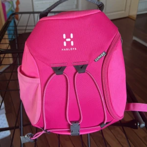 Rosa Haglöfs Corker ryggsäck mini - Säljer en snygg och praktisk rosa Haglöfs Corker mini. Den har cool form, smart fack på sidan, justerbara axelremmar och dragkedja. Perfekt för förskola eller mindre utflykter. 