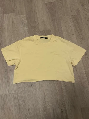 Gul croppad t-shirt från Bik Bok - Snygg ljusgul croppad t-shirt från Bik Bok. Klassisk rund halsringning och korta ärmar. Perfekt till höga jeans eller shorts. Tillverkad i mjuk bomull för en skön känsla hela dagen.