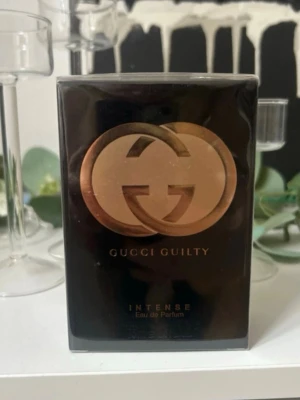 Gucci Guilty Intense Eau de Parfum - Gucci Guilty Intense Eau de Parfum kommer i en elegant svart och guld förpackning med den ikoniska dubbla G-loggan i metallic. Flaskan har en lyxig känsla och passar perfekt för dig som gillar exklusiva dofter med en djup och intensiv karaktär.