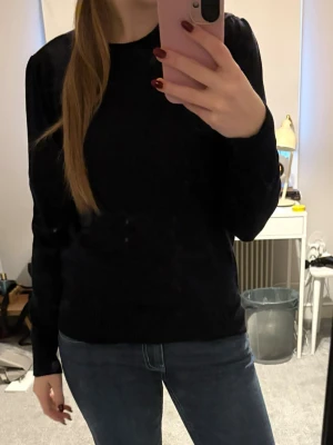 Mörkblå enkel stickad tröja - Säljer en mörkblå stickad tröja med rund hals och långa ärmar. Tröjan har en klassisk, rak passform och ribbade muddar vid ärmslut och nederkant. Perfekt att matcha med jeans för en clean look.